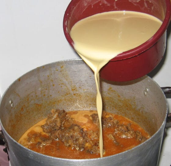 Adding raw corn starch (Ogi akamu) to boiling pot of stew